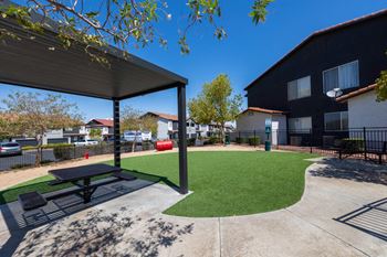 A black and white picnic table is in the middle of a green lawn.