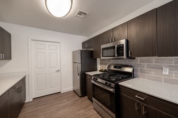 A kitchen with dark wood cabinets and a black stove top oven.
