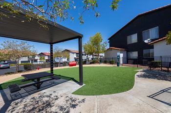 A black and white picnic table is in the middle of a green lawn.