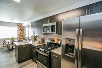 A modern kitchen with stainless steel appliances and a dining table.