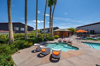 A pool surrounded by palm trees and orange chairs.