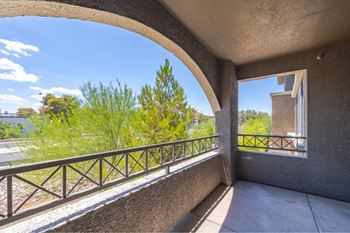 A balcony with a metal railing and a view of trees and a building.