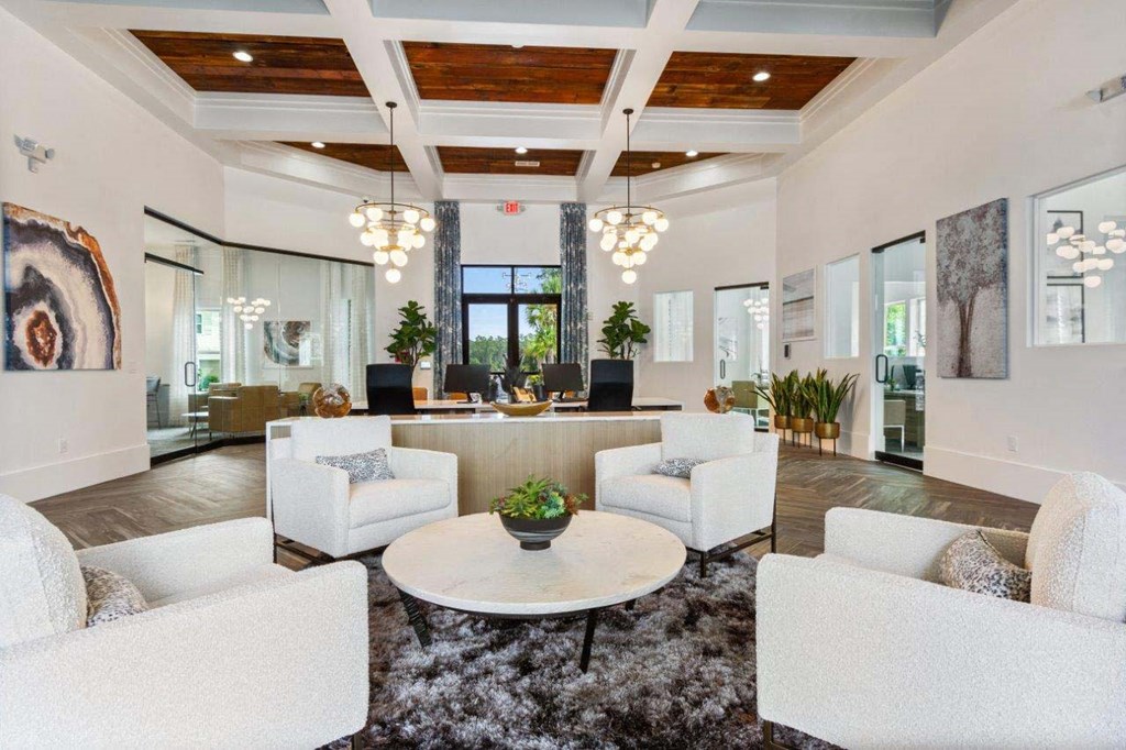 A spacious living room with white furniture and a large rug.