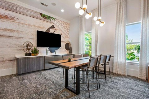 A modern living room with a wooden table and chairs, a flat-screen TV, and a wooden wall.