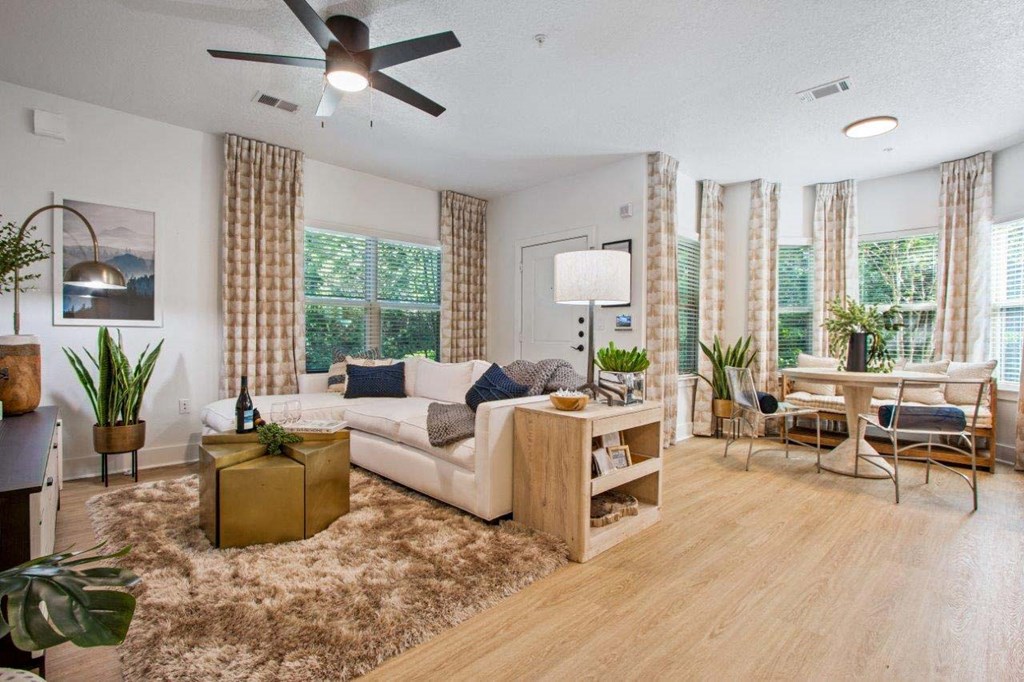 A living room with a white couch, a wooden coffee table, and a ceiling fan.