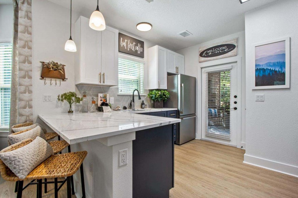 A kitchen with a white countertop and a fridge.