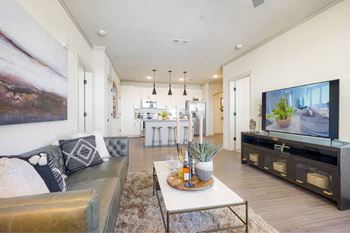A modern living room with a grey sofa, a coffee table, and a large painting on the wall.