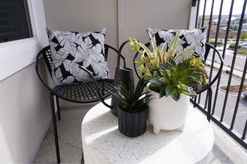 A black and white cushion is on a chair on a balcony.