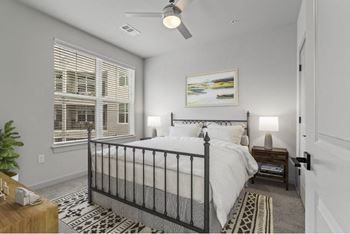 A bedroom with a large bed, a ceiling fan, and a window with blinds.