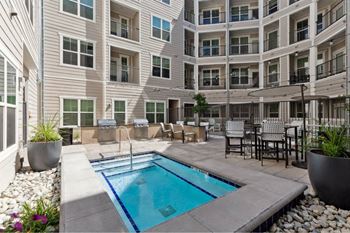 A small pool in a courtyard surrounded by chairs and plants.