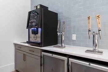 A black coffee machine is on a counter with two taps and two beer taps in front of it.