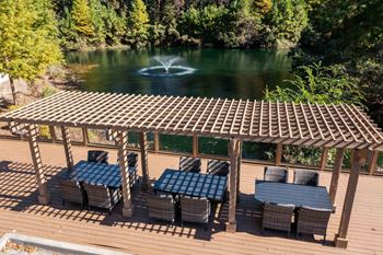 A wooden deck with tables and chairs overlooking a lake.