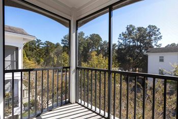 A balcony with a metal railing and a view of trees and houses.