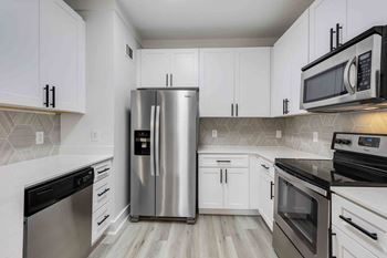 A kitchen with a stainless steel refrigerator and black and white cabinets.
