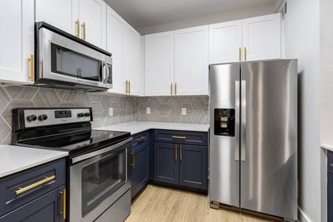 A modern kitchen with a stainless steel refrigerator and black and white appliances.