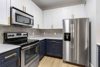 A modern kitchen with dark blue cabinets and stainless steel appliances.