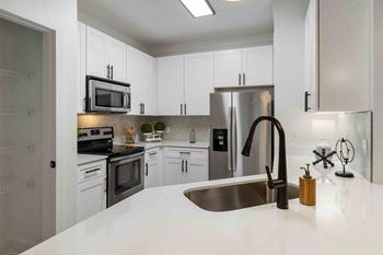 A modern kitchen with a stainless steel refrigerator, microwave, and oven.
