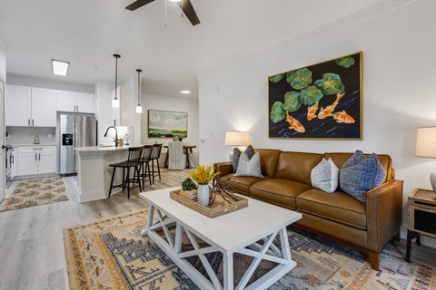 A living room with a brown couch and a painting of broccoli on the wall.