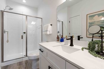 A white bathroom with a glass shower door and a white toilet.