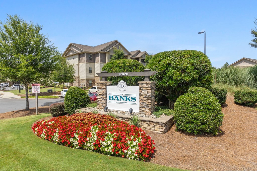 A sign for Banks in front of a building with a flower bed in the foreground.