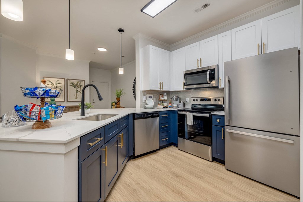 Luxury Apartments in Charlotte NC - The Banks at Rivergate - a kitchen featuring stainless steel appliances, a counter, and blue lower cabinetry