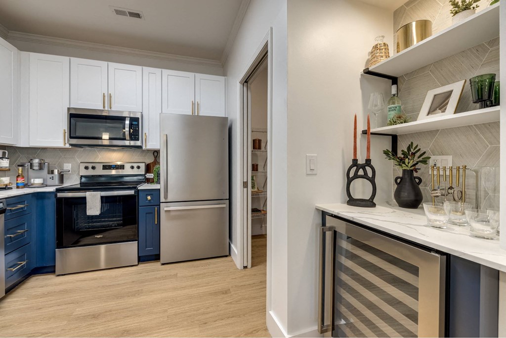 A kitchen with a refrigerator, oven, and microwave.