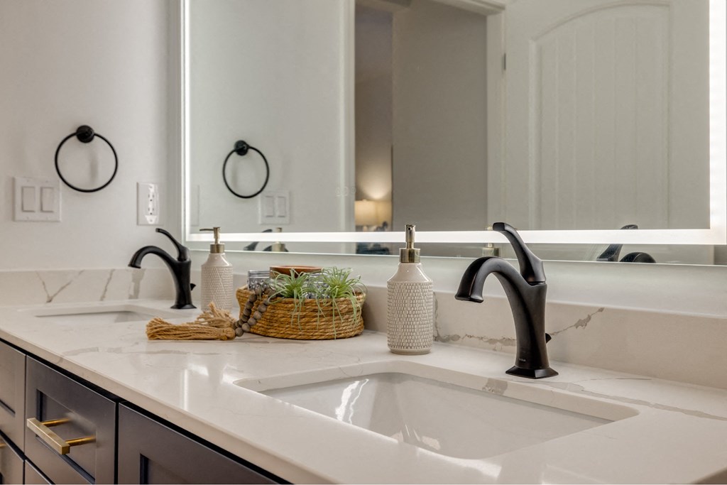A bathroom sink with a basket of plants and a soap dispenser on the counter.