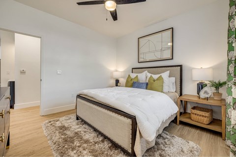 A bedroom with a large bed and a ceiling fan.