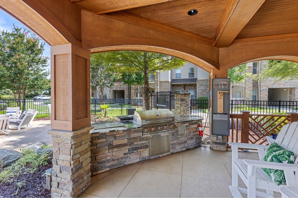 A patio with a stone wall and a grill.