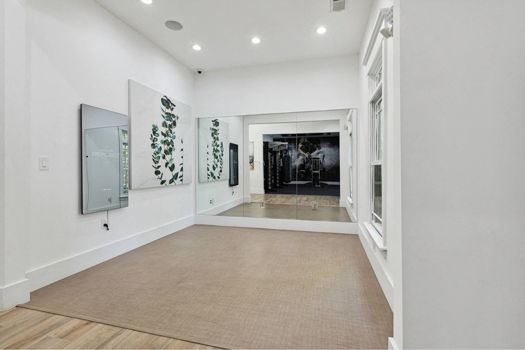 A hallway with a carpeted floor and a mirror on the wall.