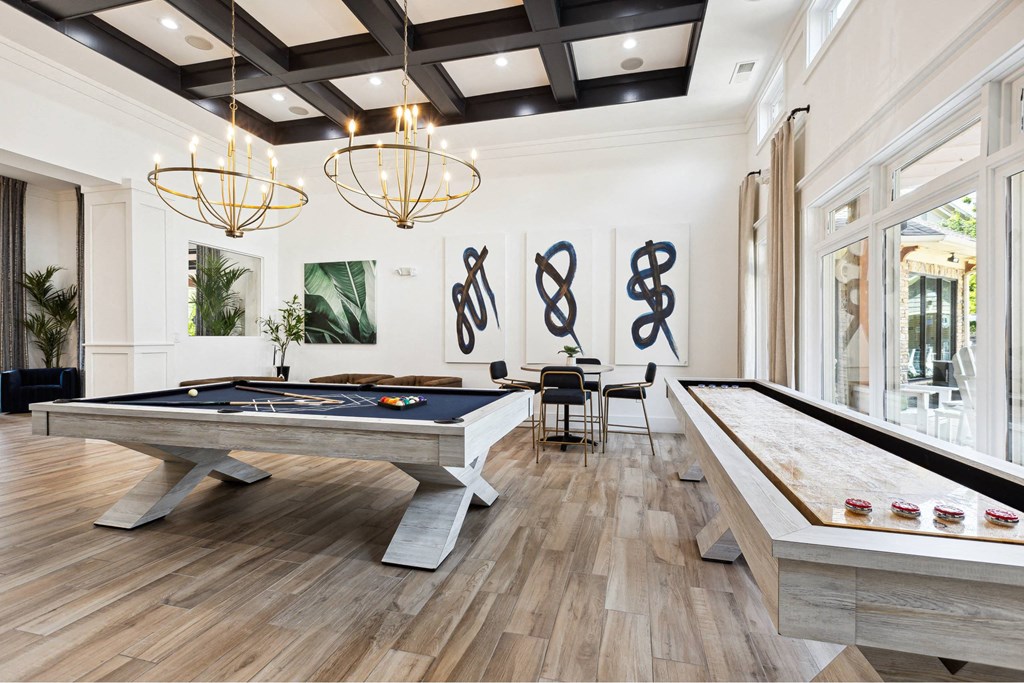 A pool table is in the middle of a room with a wooden floor and a black ceiling.