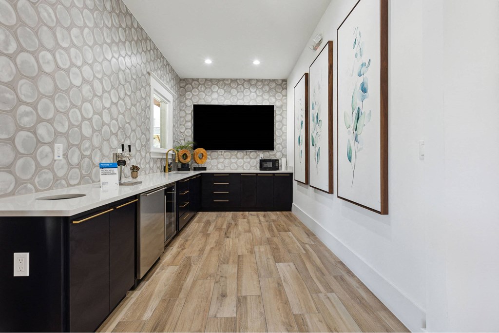 A modern kitchen with a wooden floor and black cabinets.