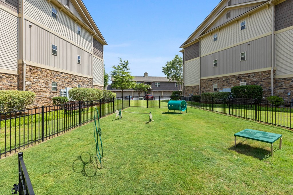 Dog-Friendly luxury apartments in Charlotte NC - The Banks at Rivergate -A black fence surrounds a dog park with a green lawn and a bench.