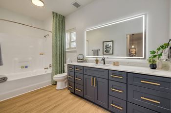 A bathroom with a white tub, sink, and a mirror.