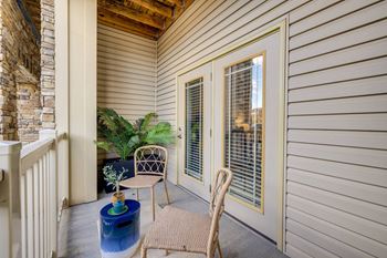 A patio with a chair, table, and potted plant.