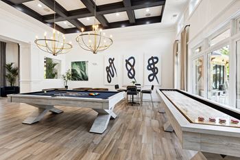 A pool table in a room with a wooden floor and a black and white striped carpet.