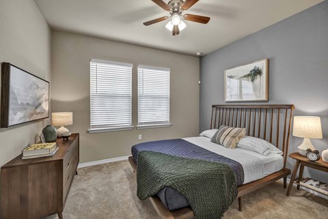 A bedroom with a bed, nightstand, and a ceiling fan.