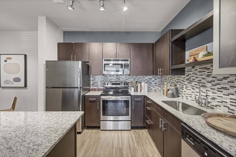 A modern kitchen with stainless steel appliances and wooden flooring.