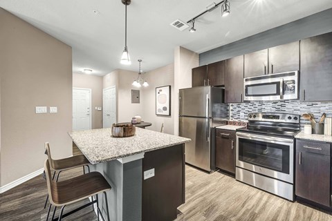 A kitchen with a granite countertop and stainless steel appliances.