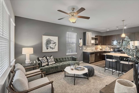 A living room with a grey couch, a coffee table, and a ceiling fan.