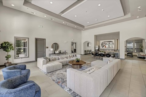 A spacious living room with a white sofa set and a blue armchair.