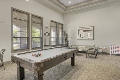 A pool table is in the middle of a room with a chair and a sofa.