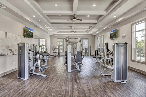 A spacious gym with a variety of equipment and a ceiling fan.
