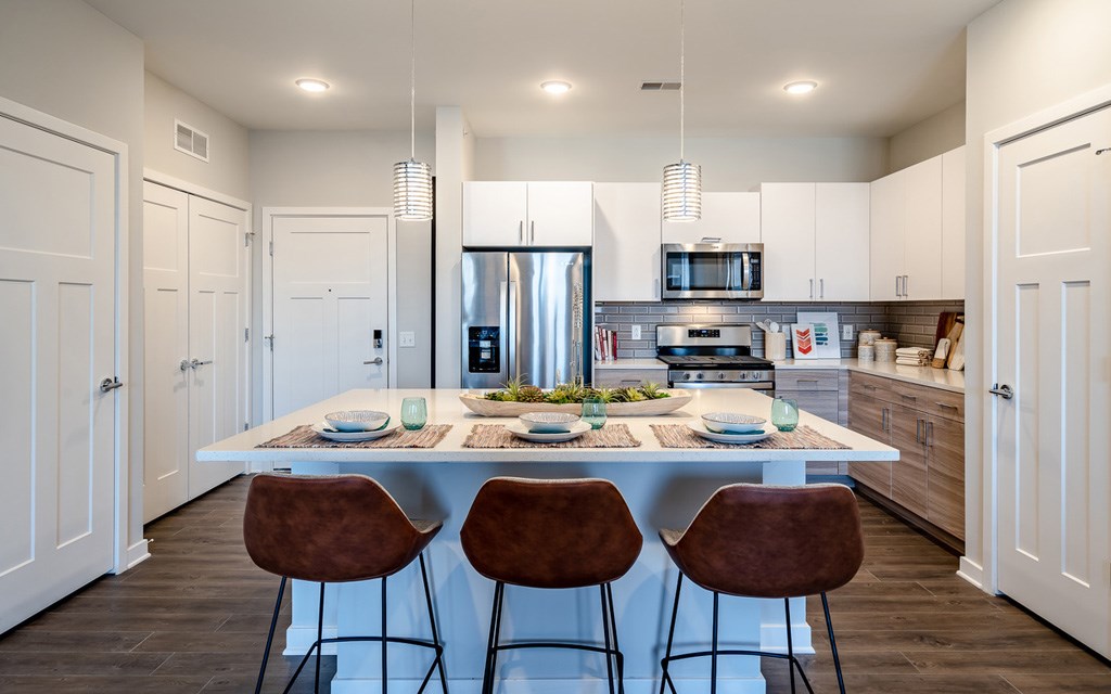 A modern kitchen with a dining table set for two.