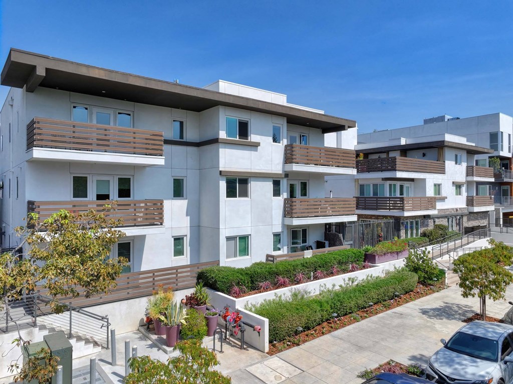 A modern apartment complex with a courtyard and parked cars.