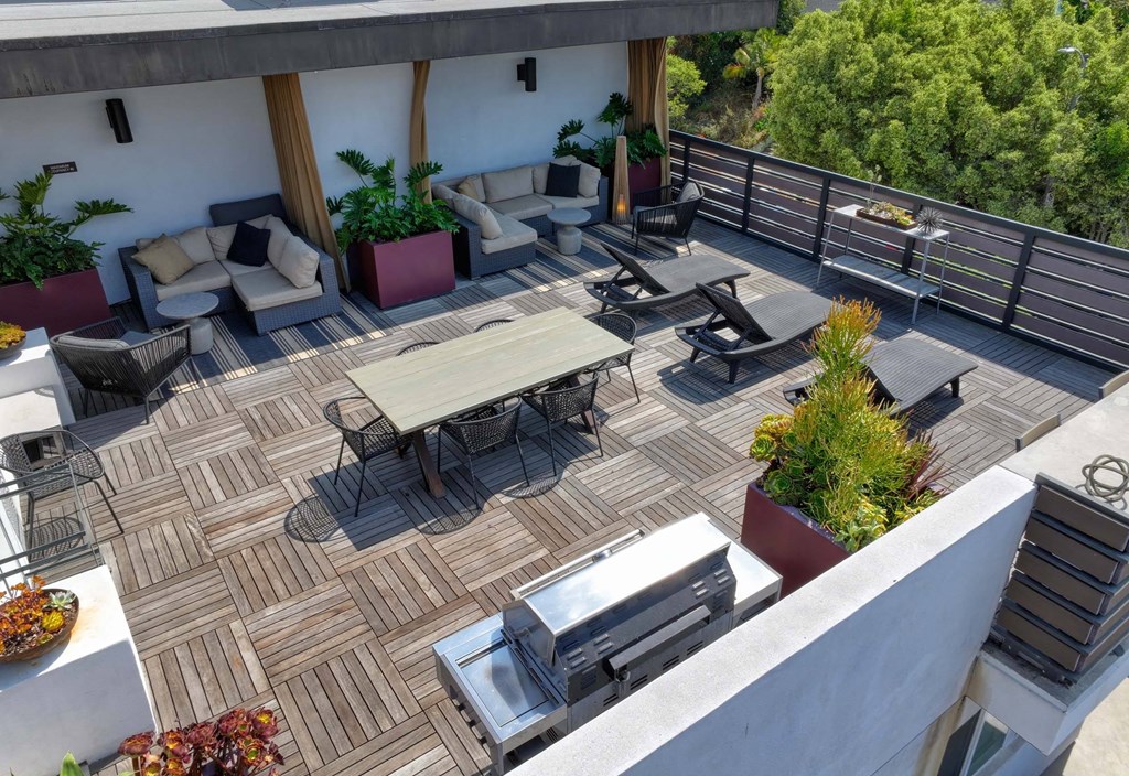 A patio with a table and chairs and a grill.