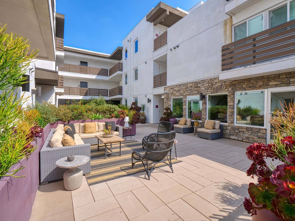 A patio with a table and chairs is surrounded by plants.