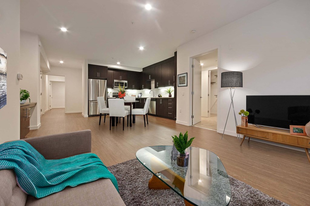 A modern living room with a grey couch and a glass coffee table.