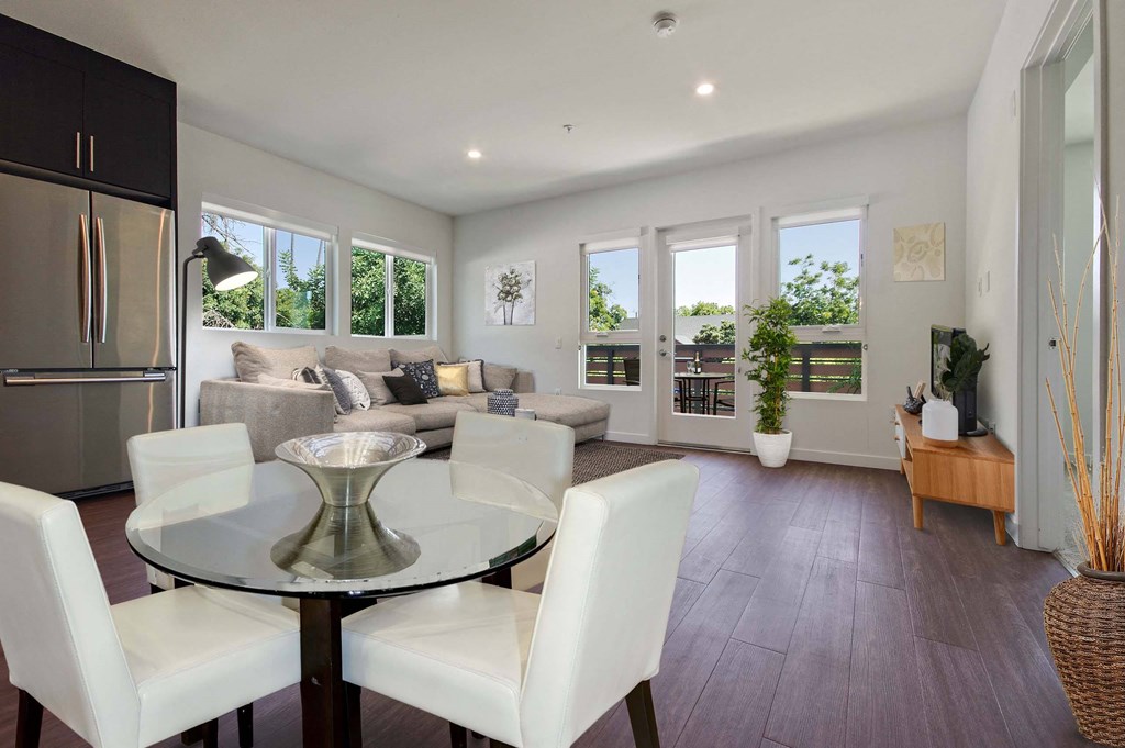 A modern dining room with a glass table and white chairs.