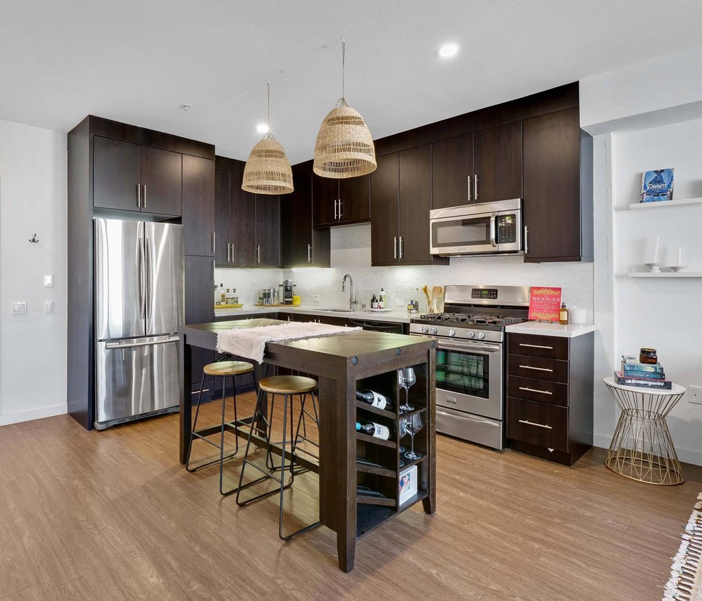 A modern kitchen with dark brown cabinets and stainless steel appliances.